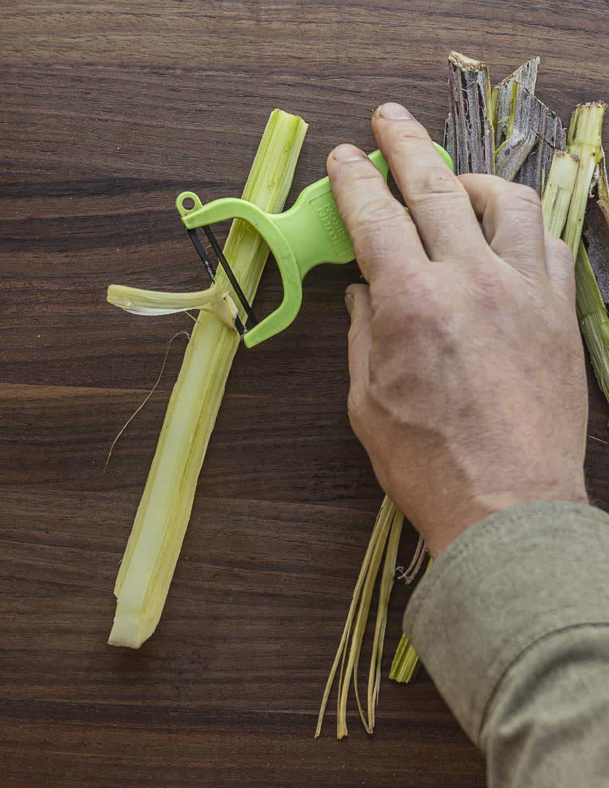 Peeling burdock flower stalks a second time to remove fibers with a vegetable peeler. 