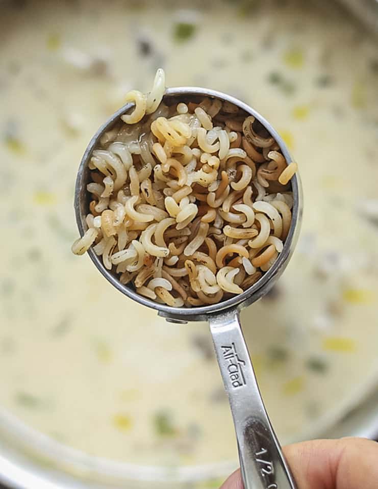 Adding cooked wild rice to a pot of morel mushroom soup. 