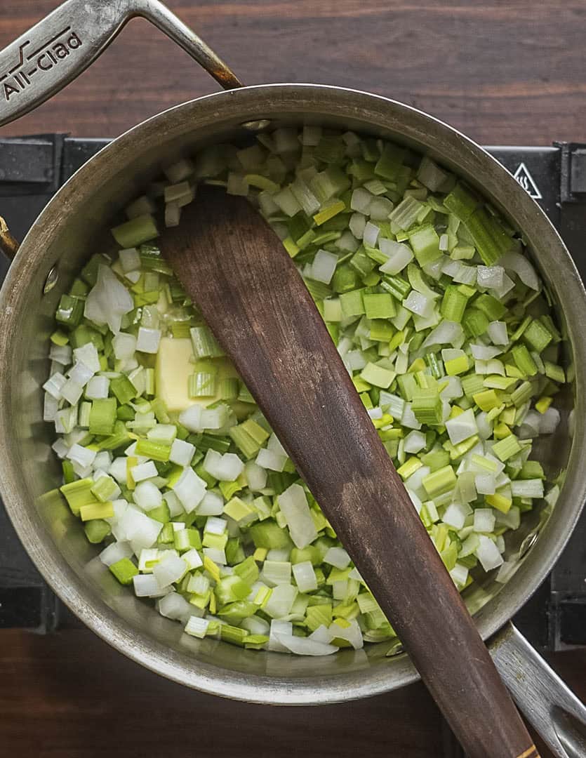 Cooking celery, onion and leek in a pot with butter. 