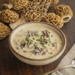 A bowl of fresh morel mushroom soup next to a pile of fresh morel mushrooms from Minnesota.