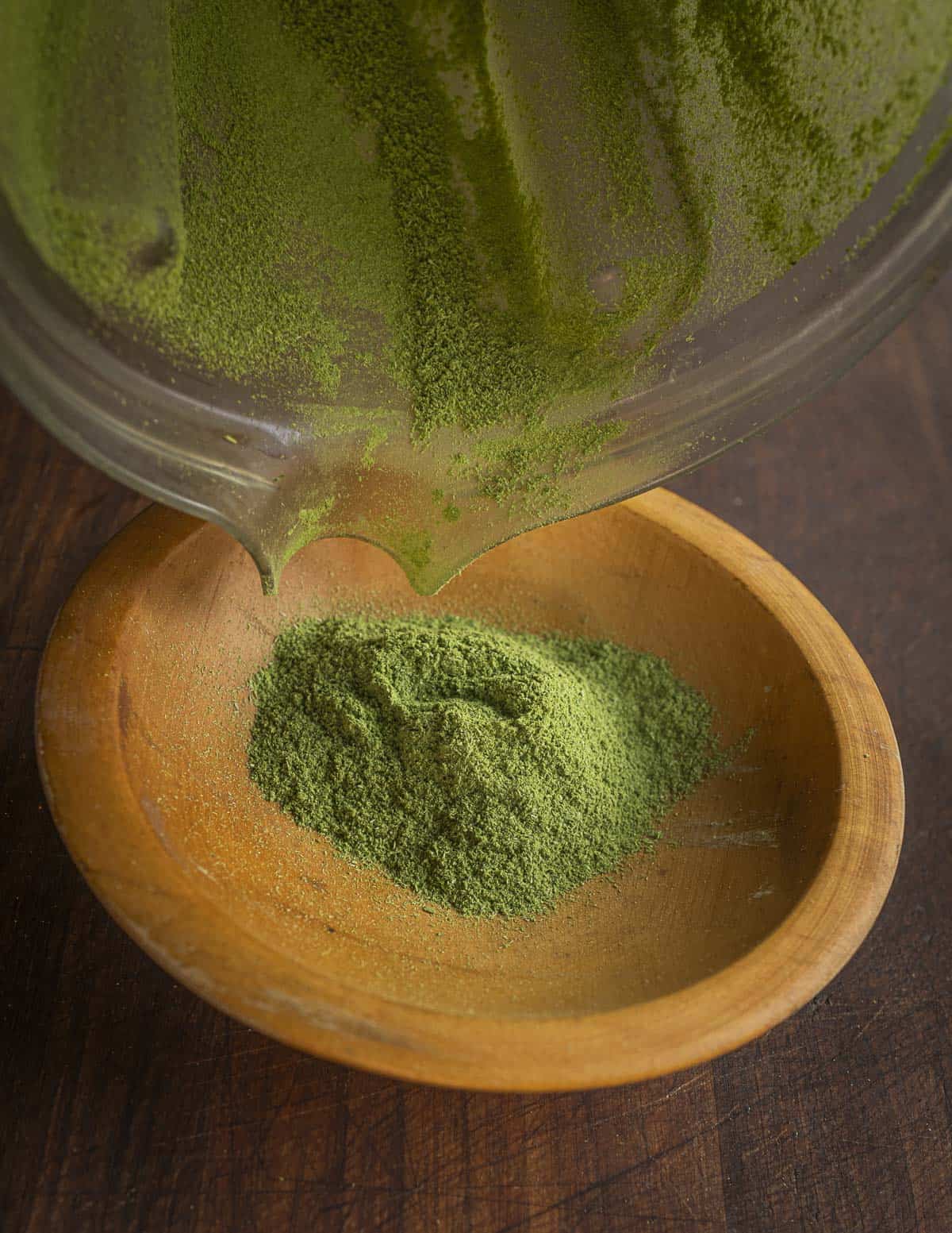 Pouring dried, ground green garlic leaf powder into a bowl. 