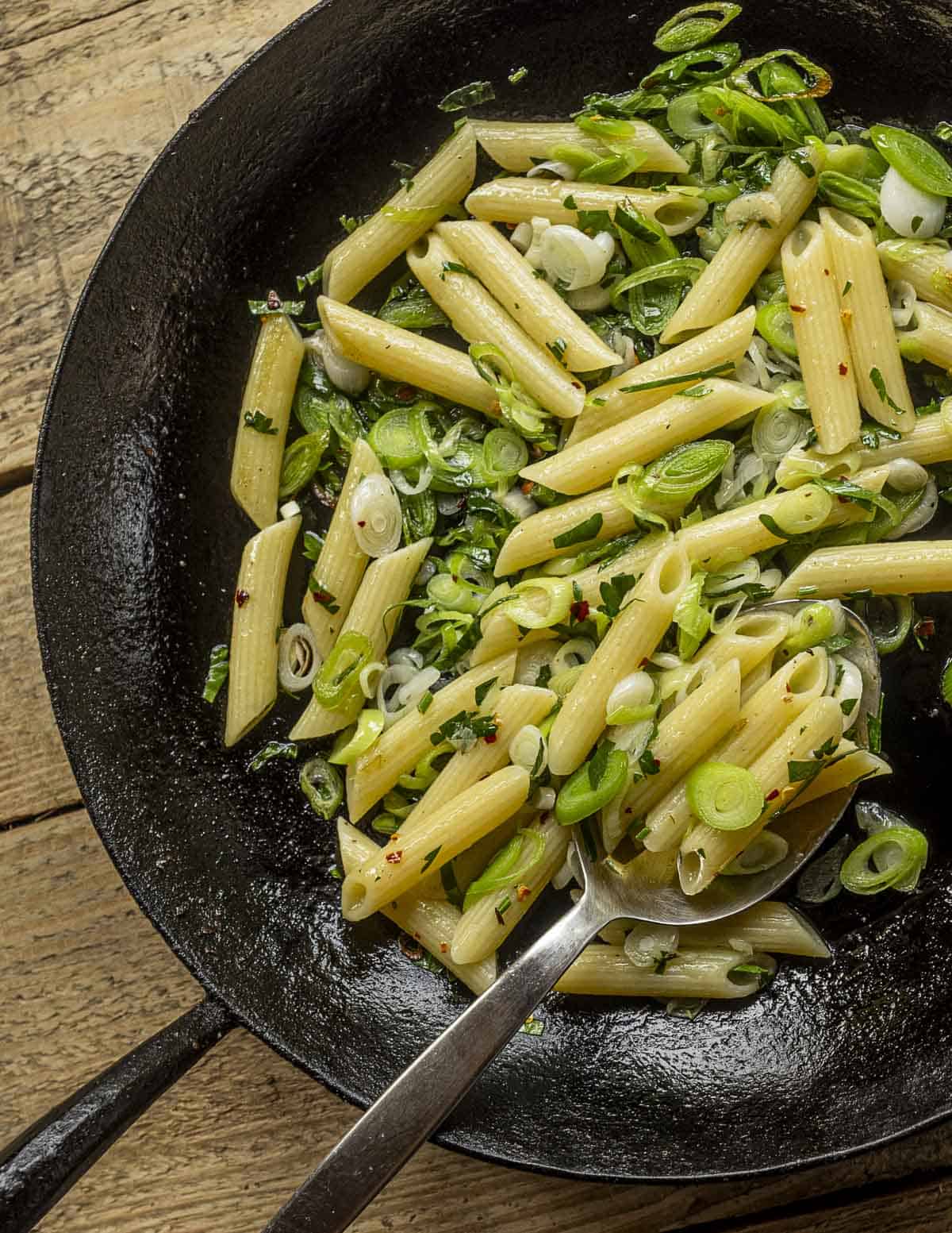 A Kehoe carbon steel pan filled with penne green garlic pasta aglio olio. 