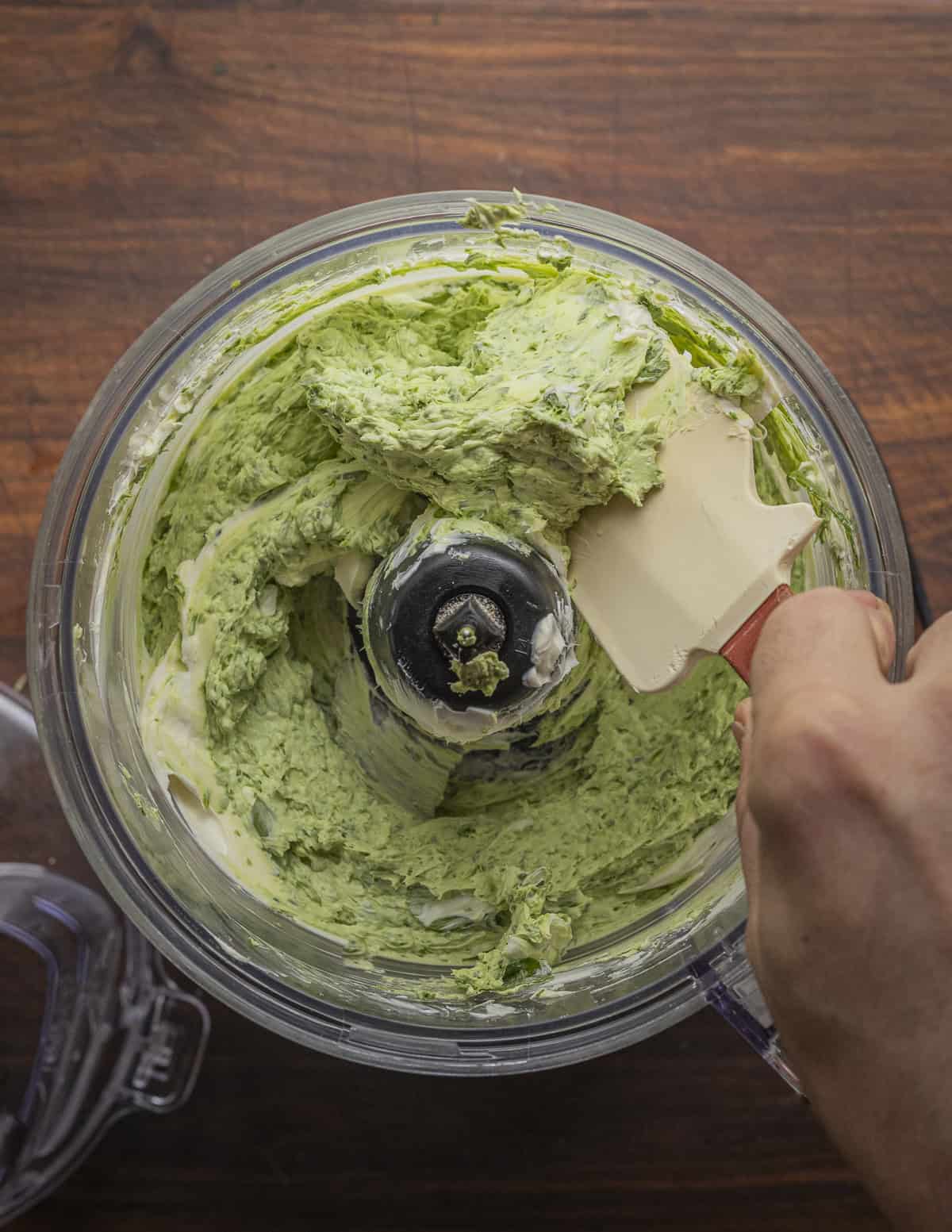 Scraping down the bottom of the food processor bowl with a spatula. 