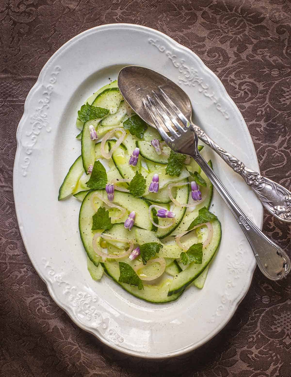 A cucumber salad with pickled shallots, lemon balm and edible comfrey flowers. 