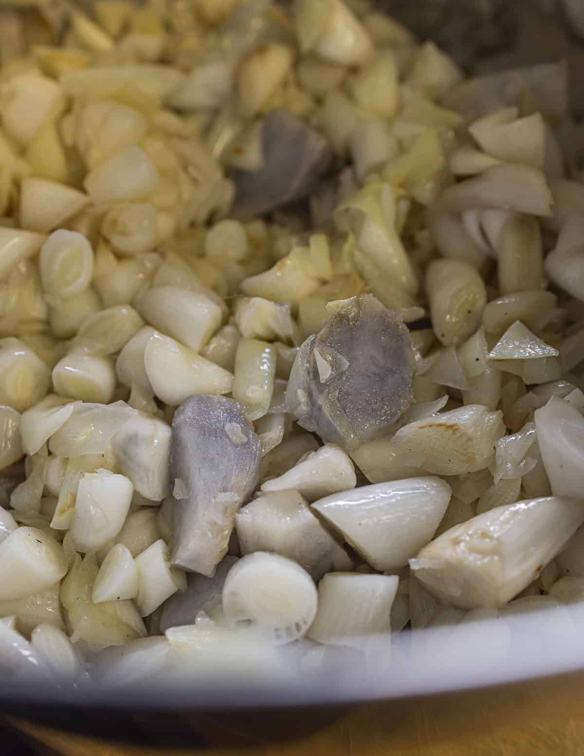 A bowl of cooked cattail shoots and slotsm showing discoloration on the slotsm due to undercooking. 