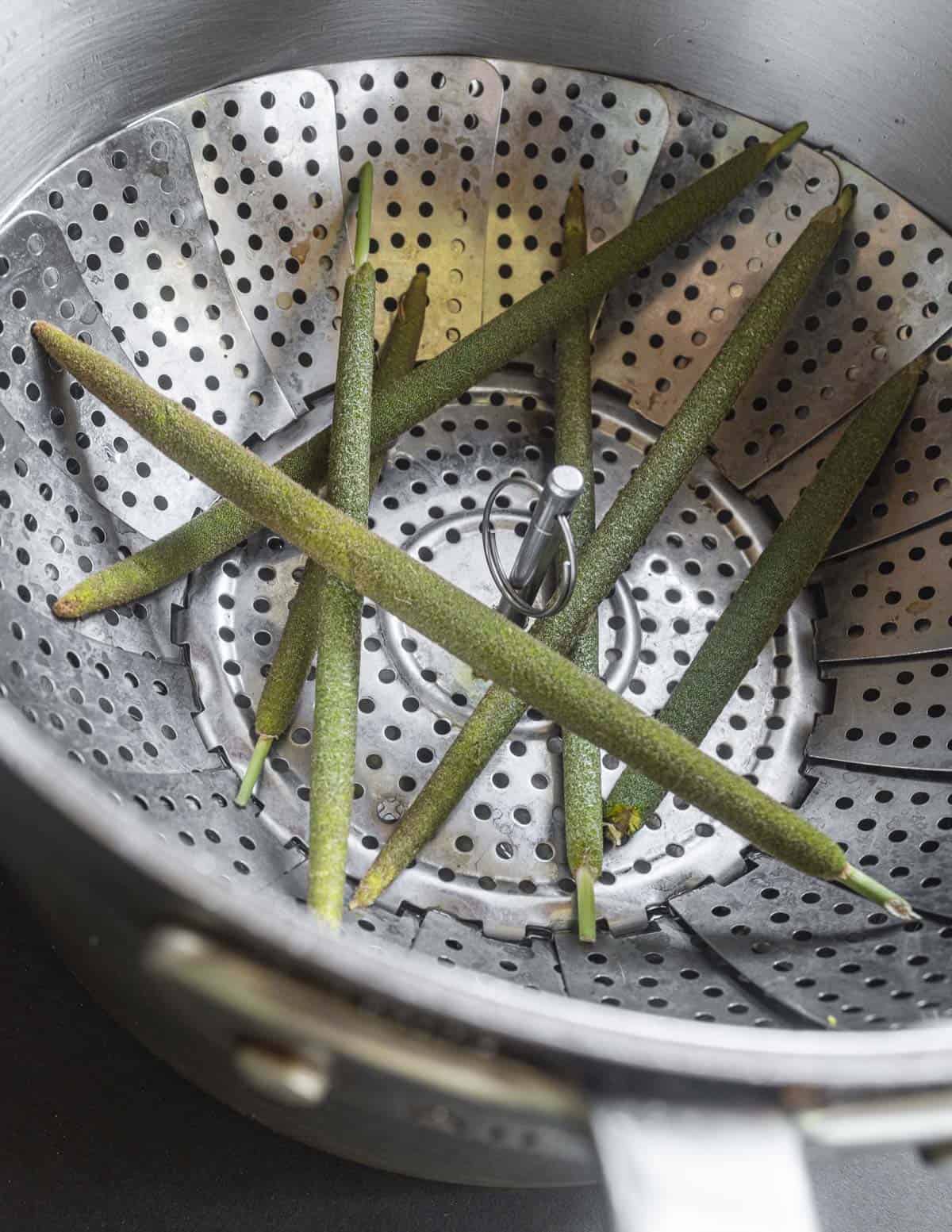 Cattail flower spikes in a steamer basket cooking. 