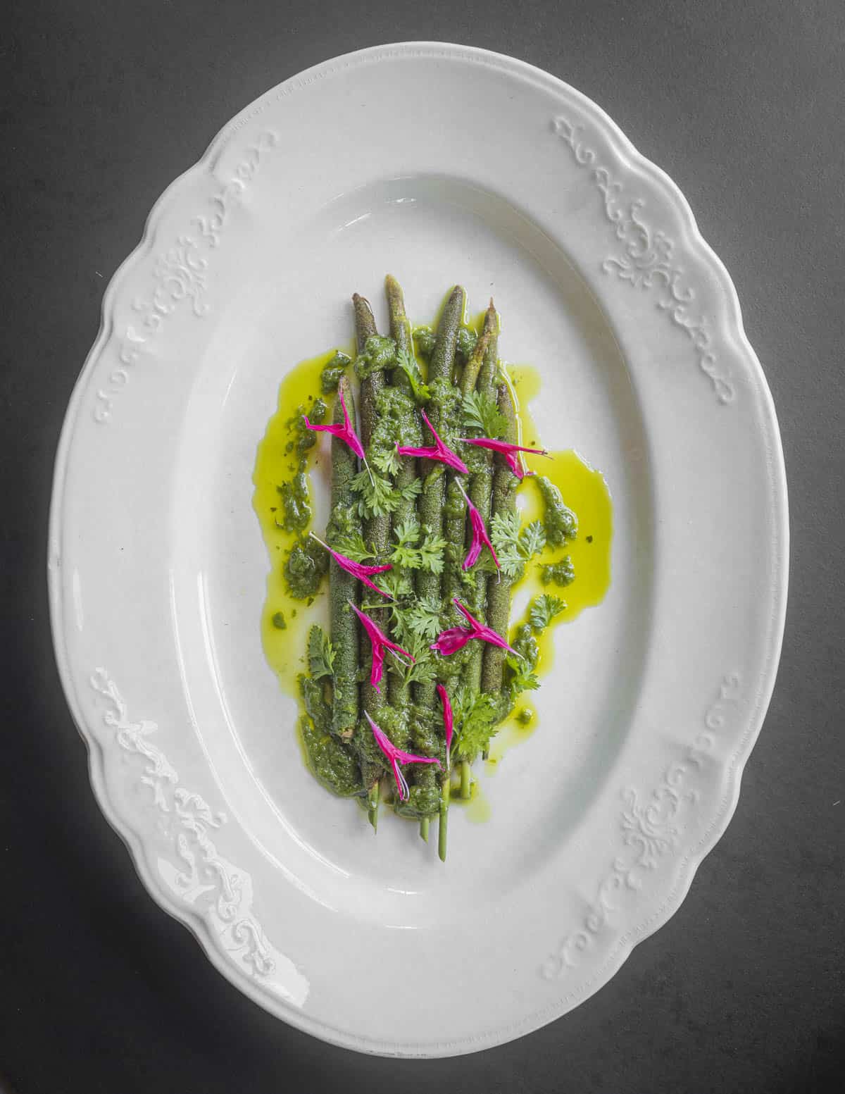 A plate with cooked cattail flower spikes garnished with ramp butter and scarlet bee balm flowers. 