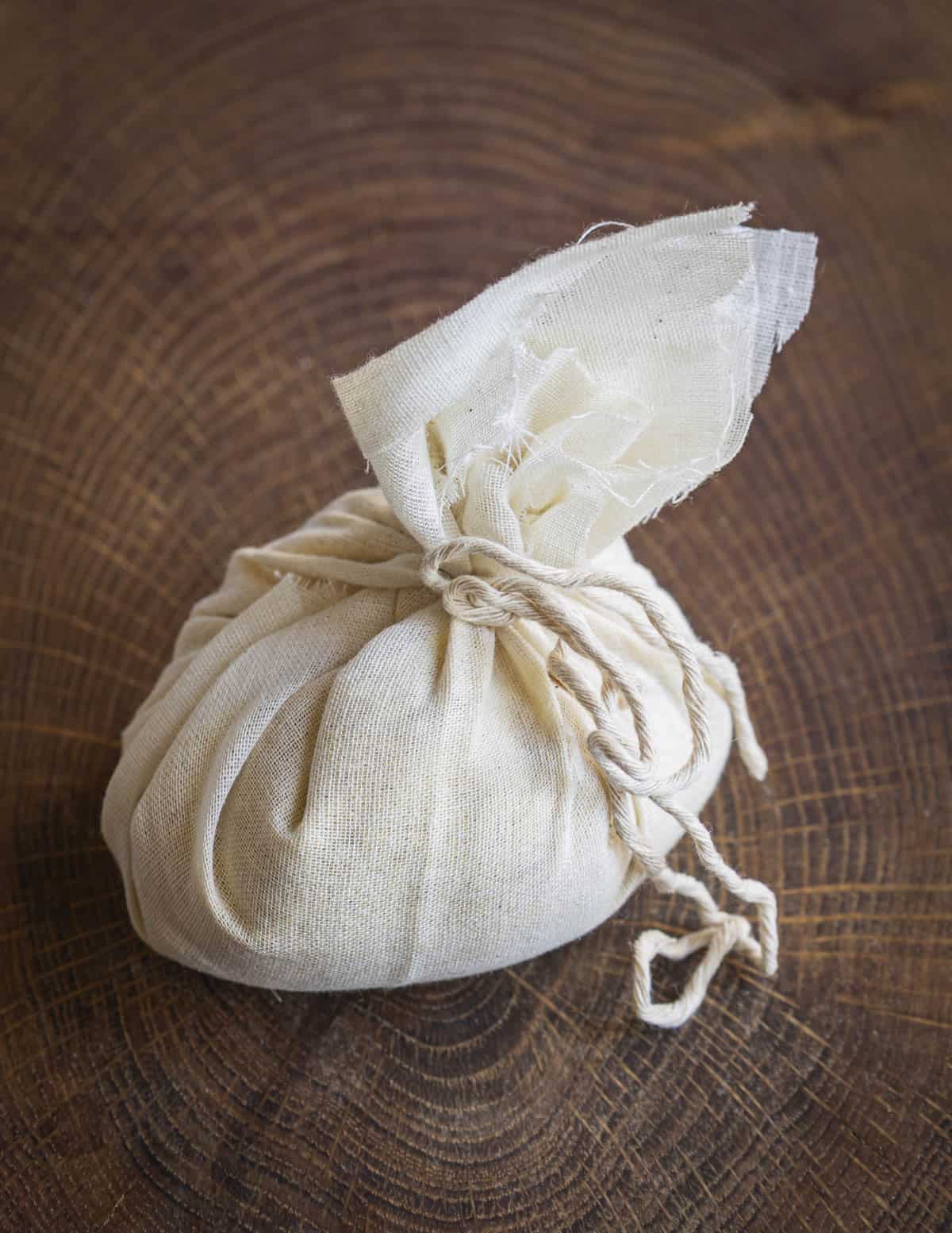 A bag of pollen mixed with sugar wrapped in cheesecloth on a cutting board. 