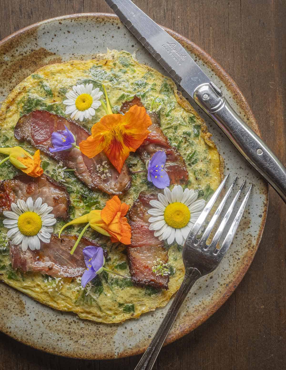 An omelet made with wild orache greens garnished with slices of fried tasso ham and nasturtium, spiderwort, cilantro and ox eye daisy flowers. 