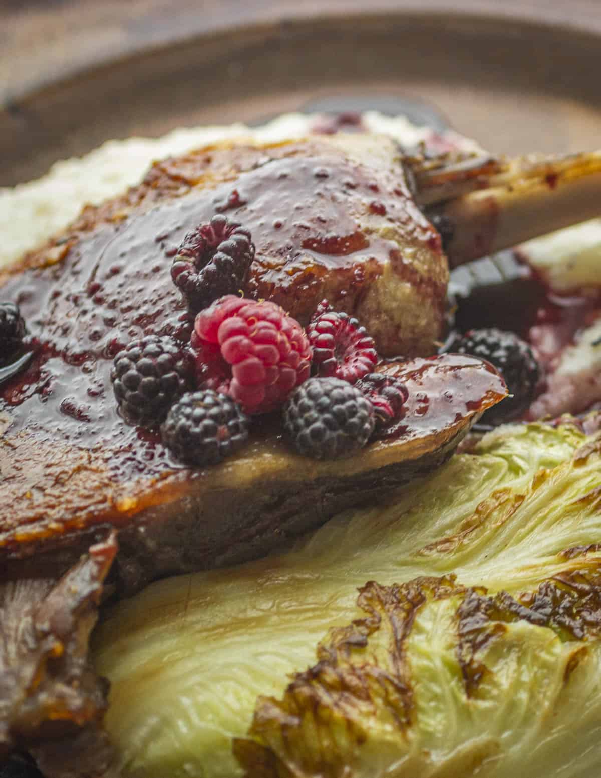 A picture of goose confit with black cap raspberry sauce and cabbage. 