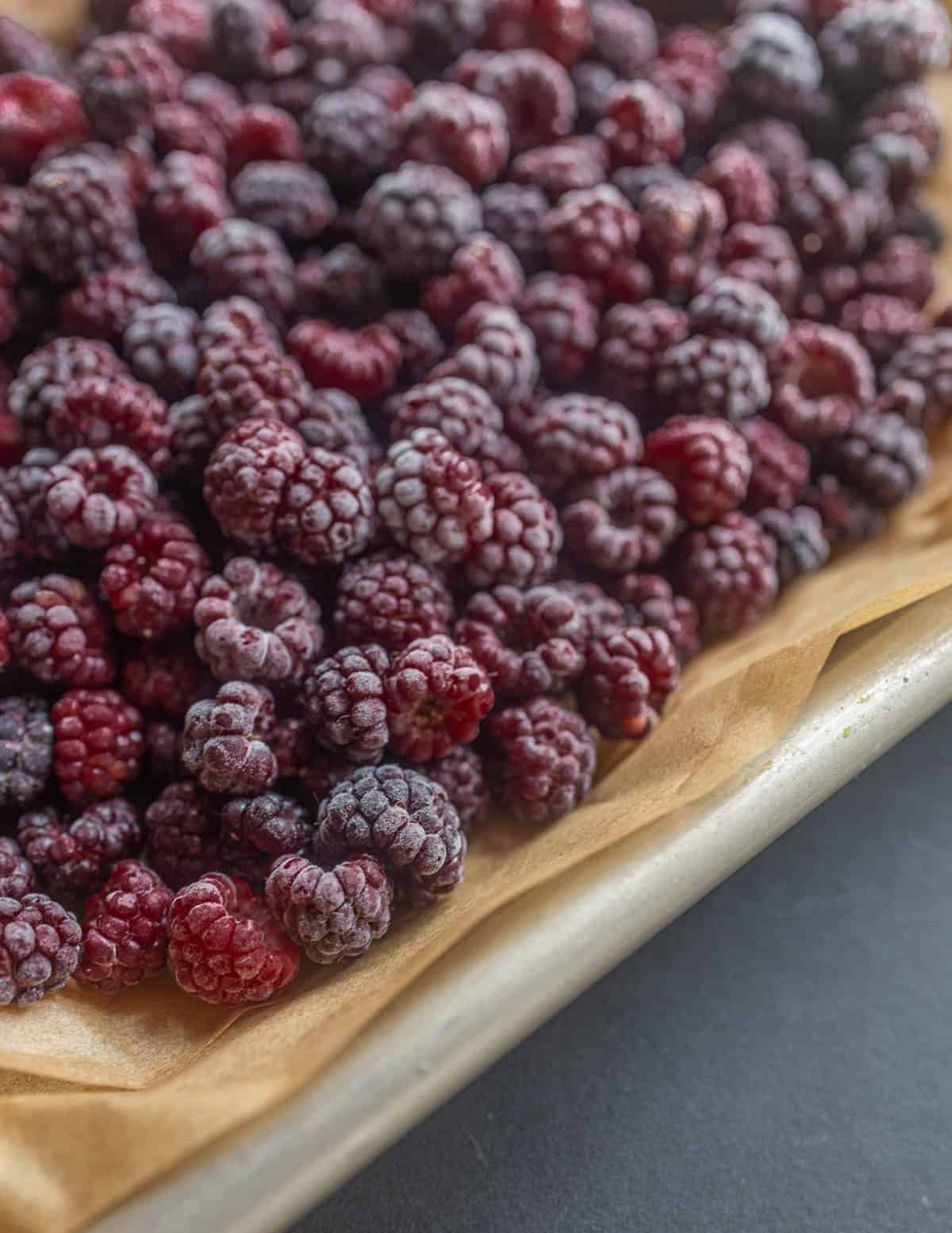 Frozen black raspberries on a baking sheet lined with parchment. 