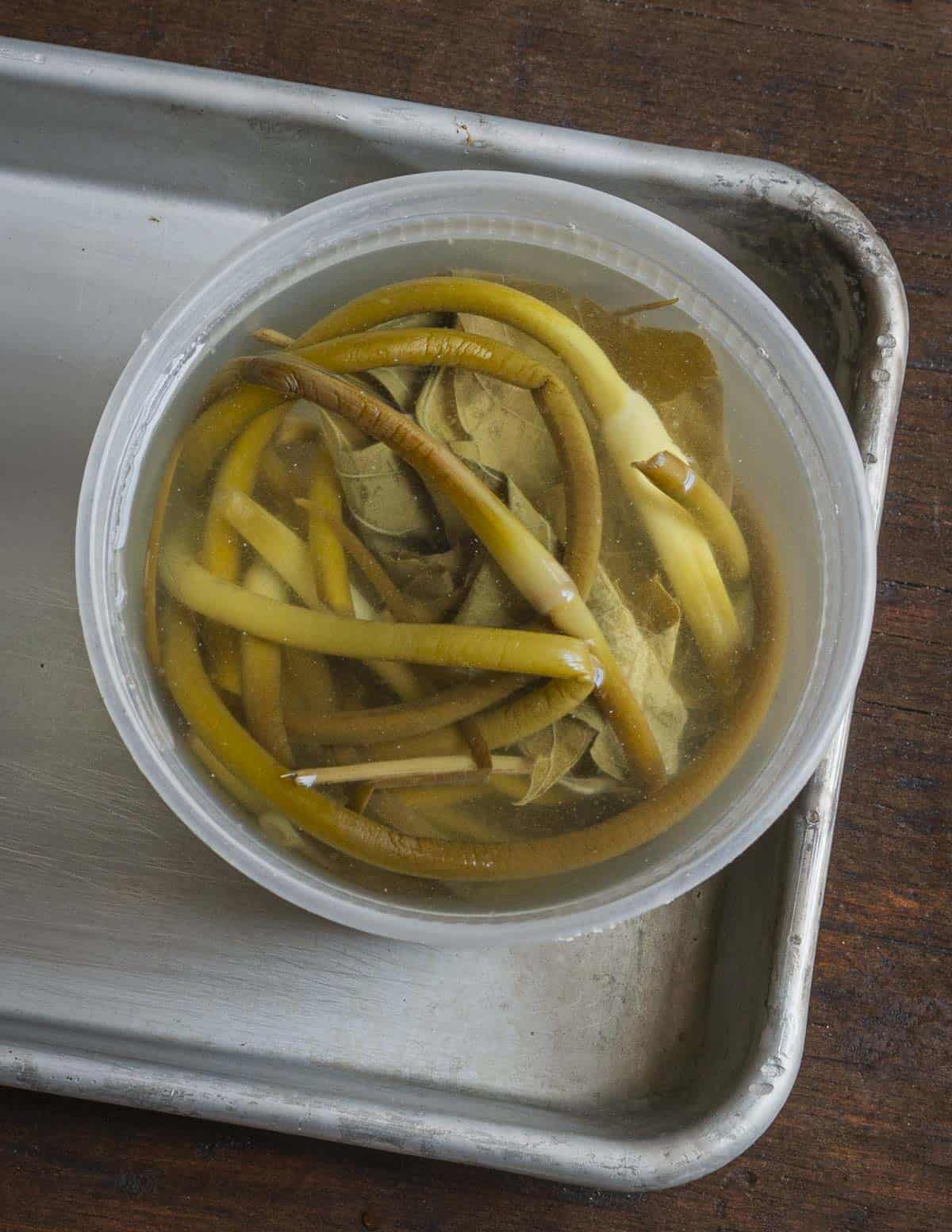 A jar of fermenting garlic scapes in brine.