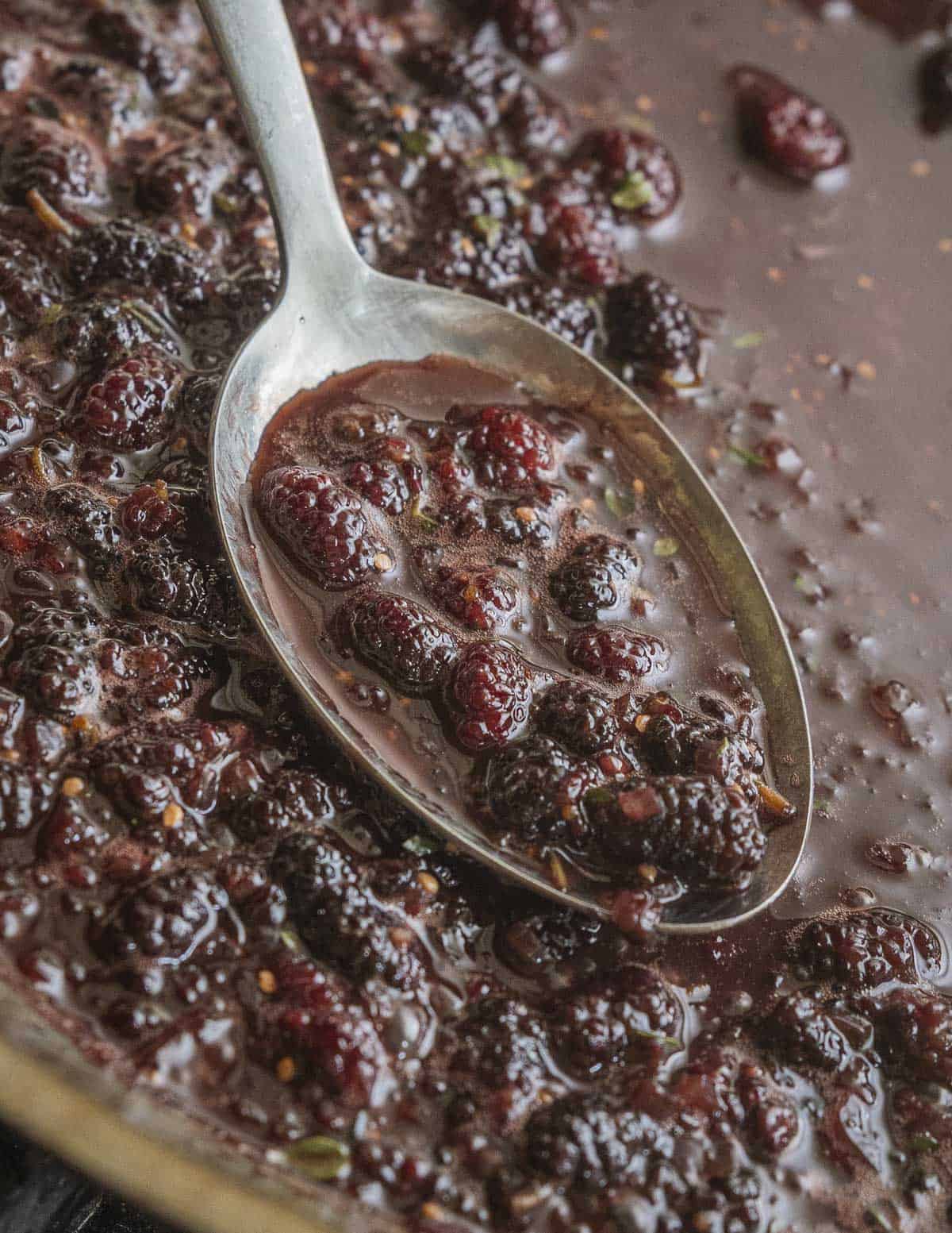 A close up of a pan of white mulberries cooking in a wine sauce. 
