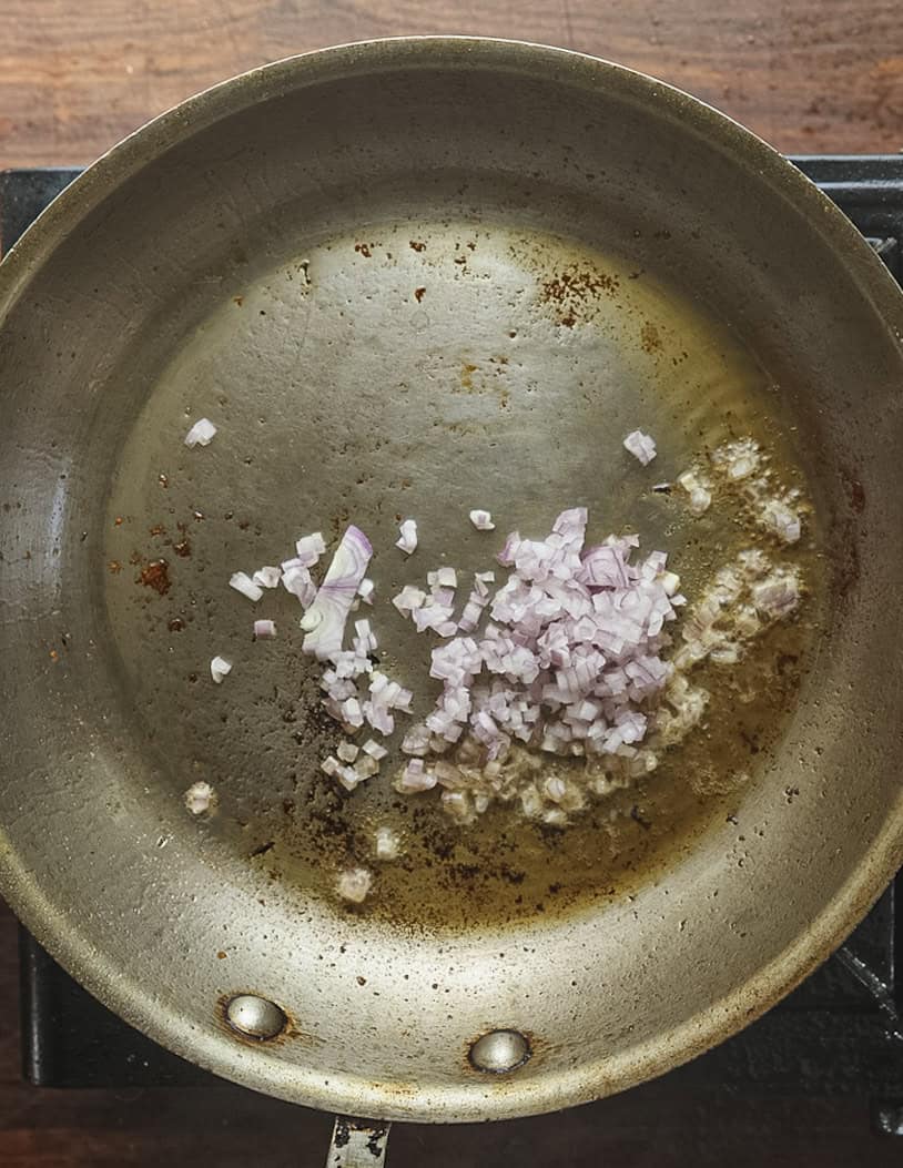 Adding finely diced shallots to a pan that a chicken was cooked in. 