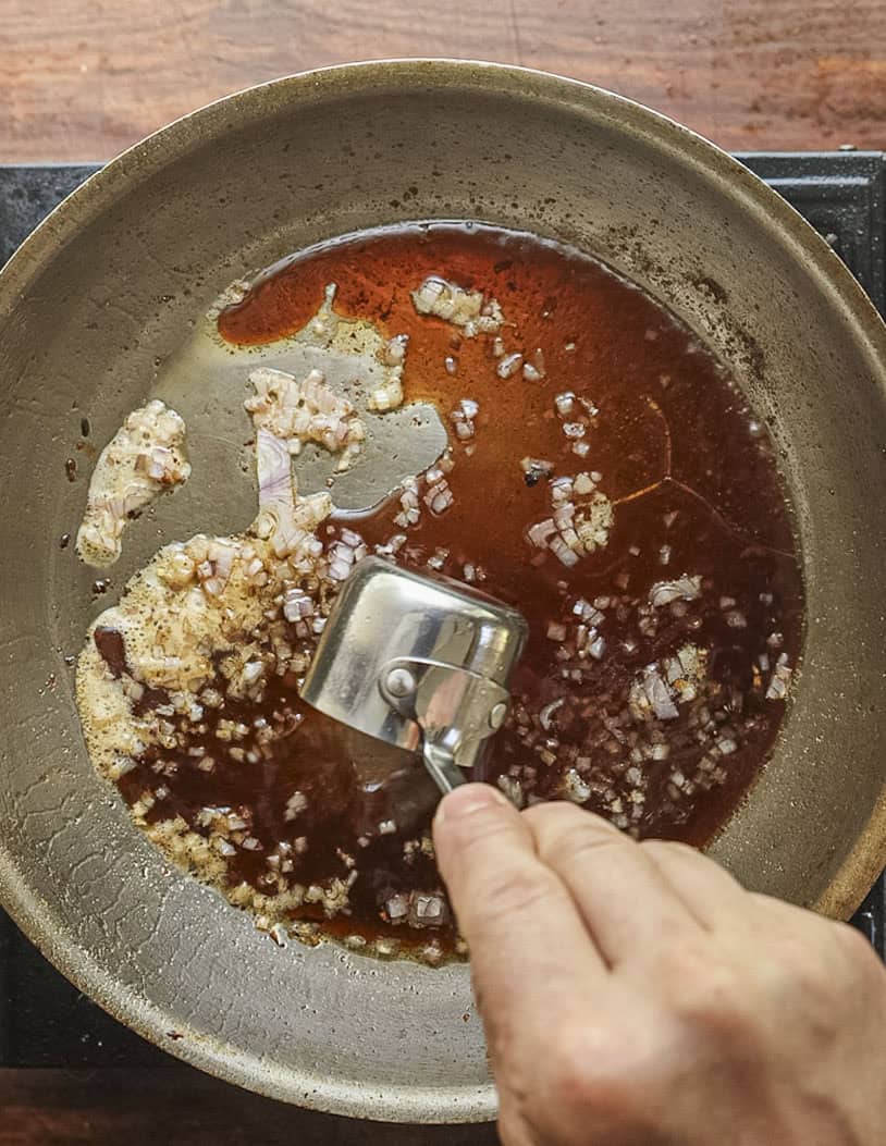 Adding mulberry vinegar to a pan of shallots. 