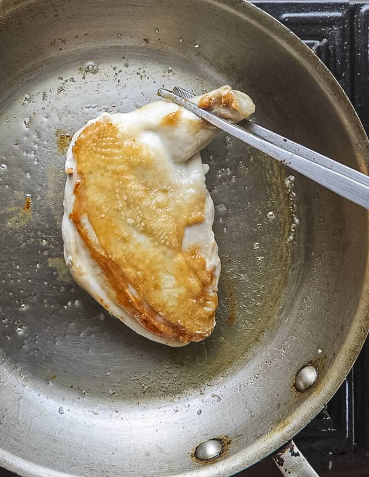 Flipping a chicken breast to ensure even cooking. 