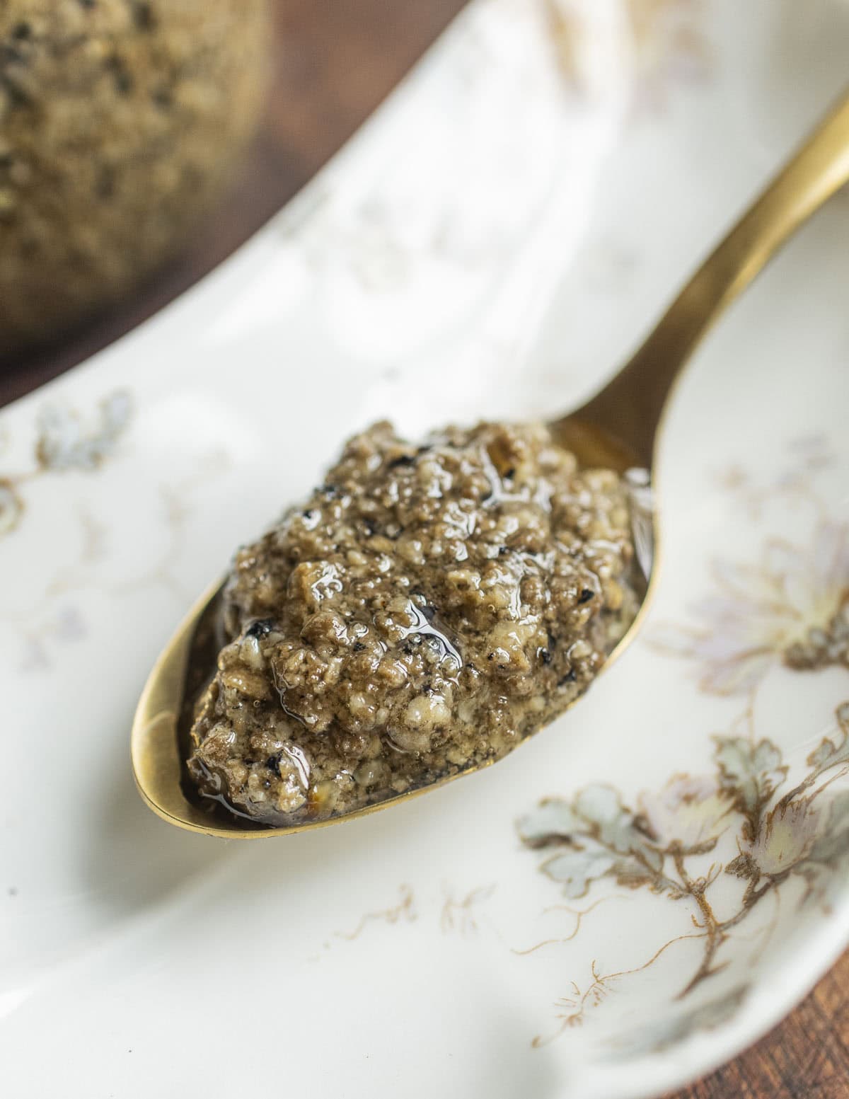 A spoon filled with tartufata truffle sauce next to a jar of truffle sauce. 
