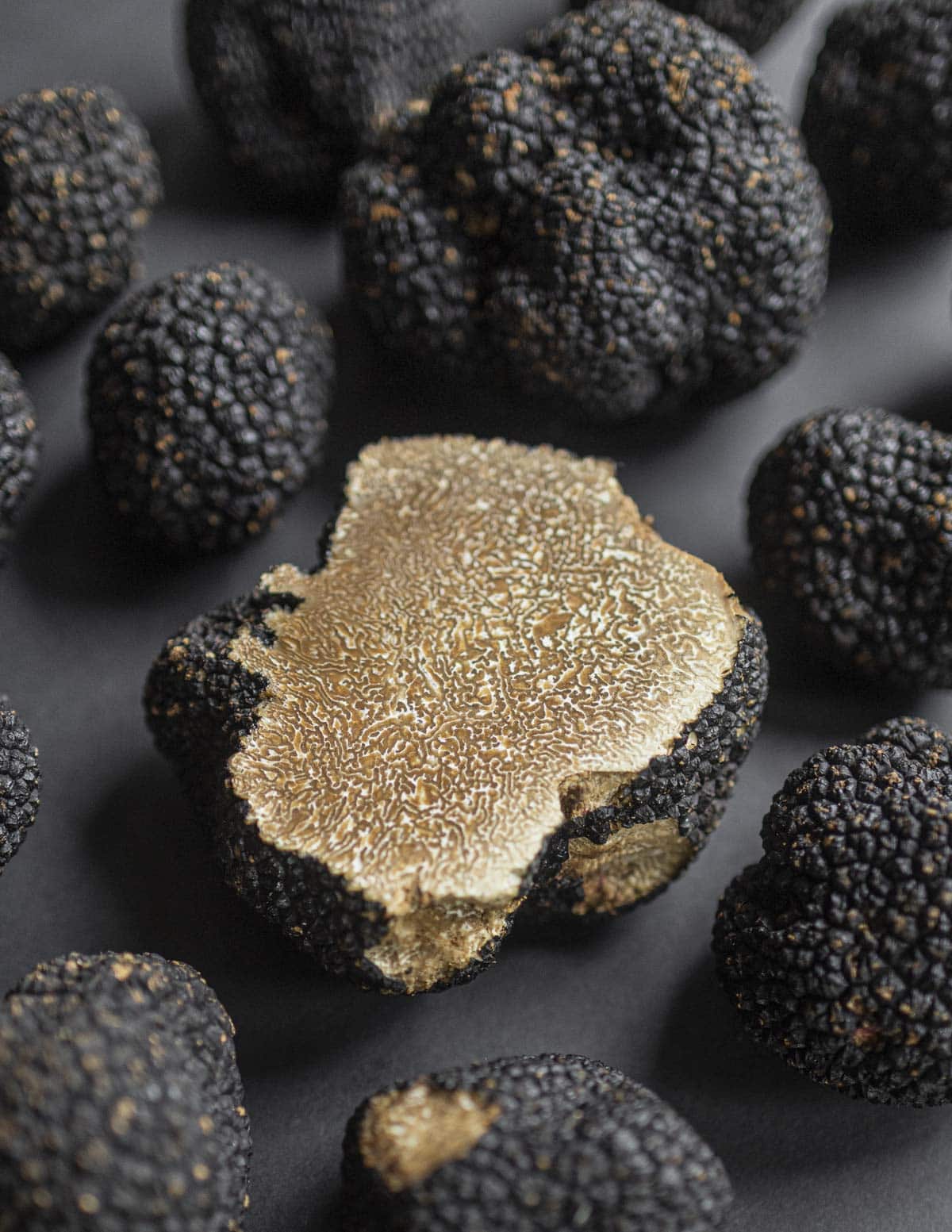 A whole cut truffle surrounded by fresh summer truffles (Tuber aestivum). 