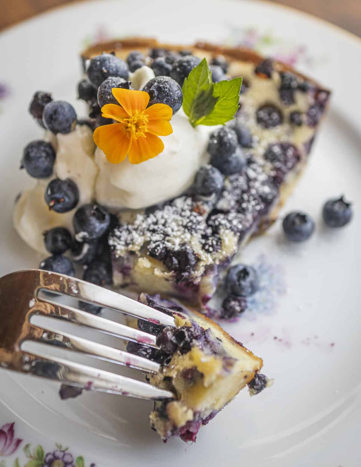A fork digging into a slice of blueberry clafoutis. 
