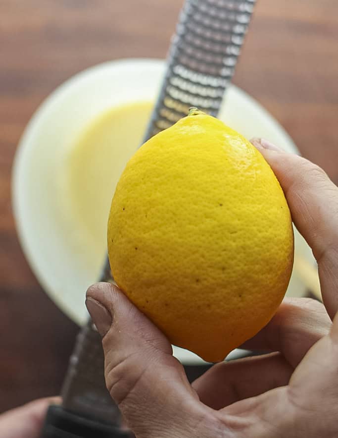 Adding grated lemon zest to a clafoutis batter. 