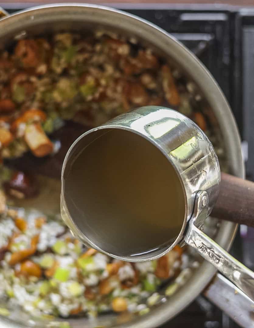Adding chicken stock to a pan of chanterelle mushroom risotto. 