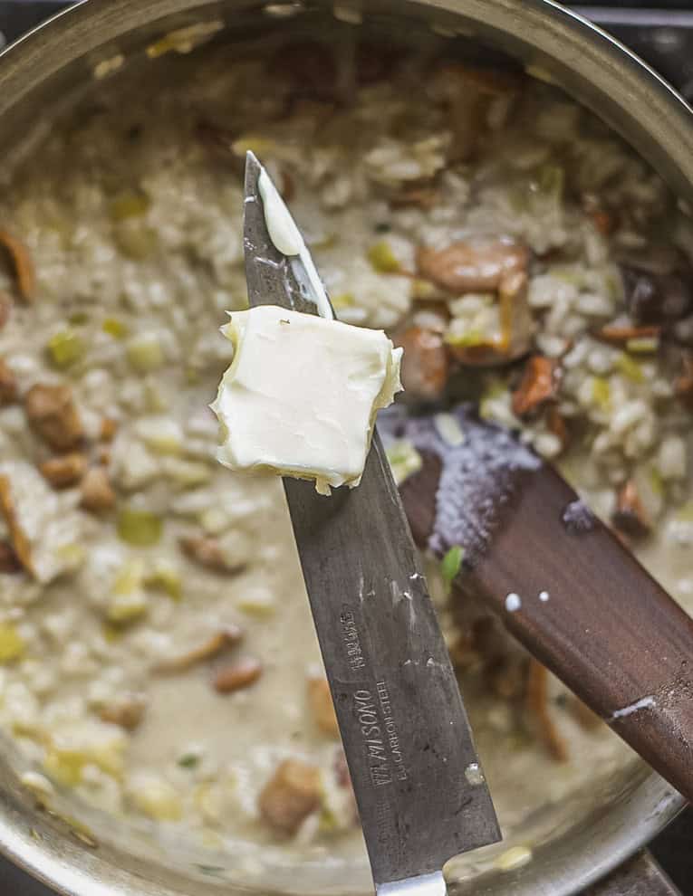 Adding unsalted butter to a risotto. 