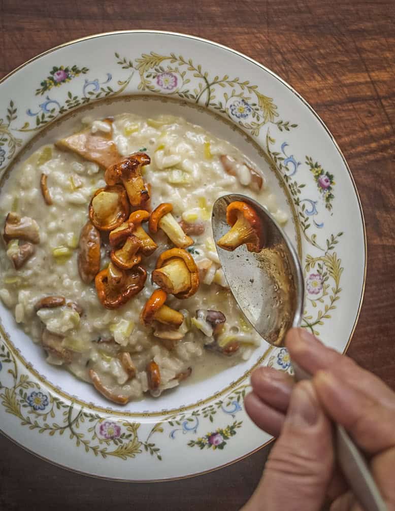 Spooning sauteed chanterelle mushrooms on top of risotto. 