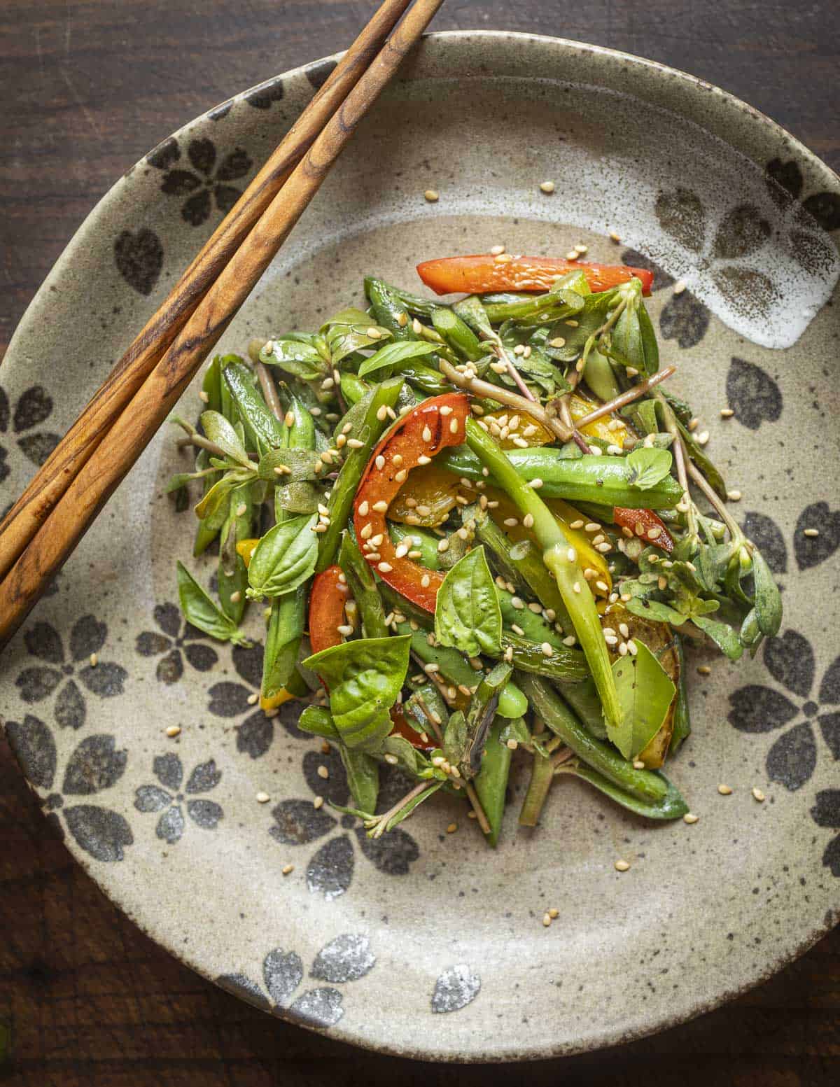A stir fry of garlic scapes and green beans garnished with purslane, basil and sesame seeds.