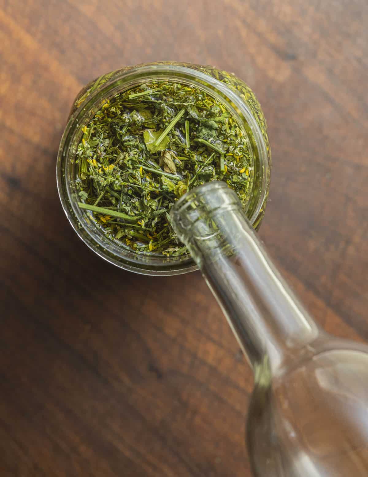Pouring brandy into a jar of dried sweet clover to make an extract. 