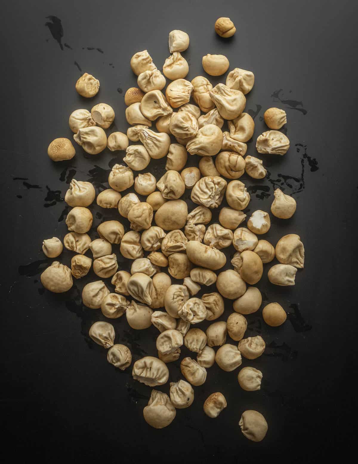 A large amount of small, edible brown puffball mushrooms after washing and trimming on a black background, ready to cook. 