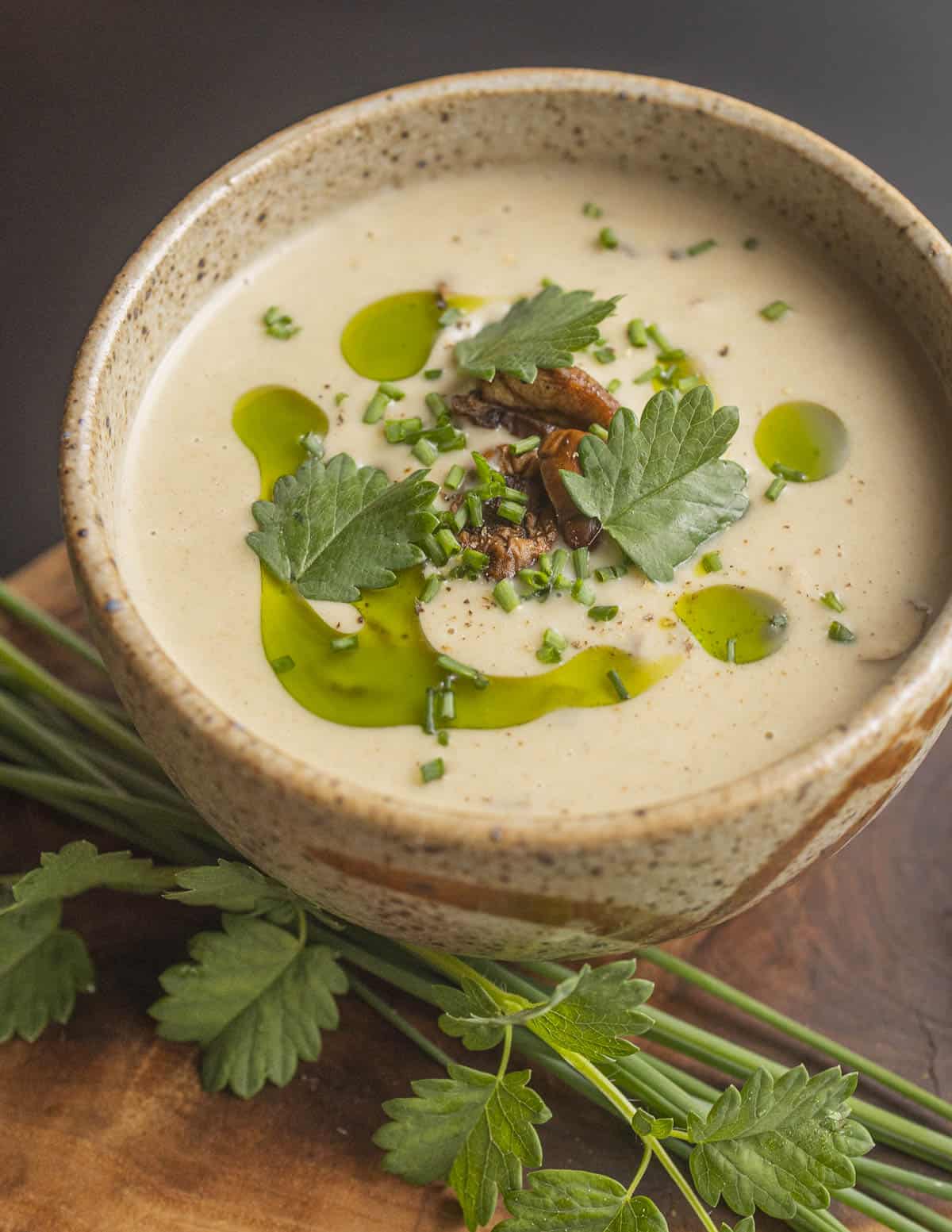 Creamy roasted garlic and puffball mushroom soup garnished with herb oil, salad burnet, chives and small puffballs. 