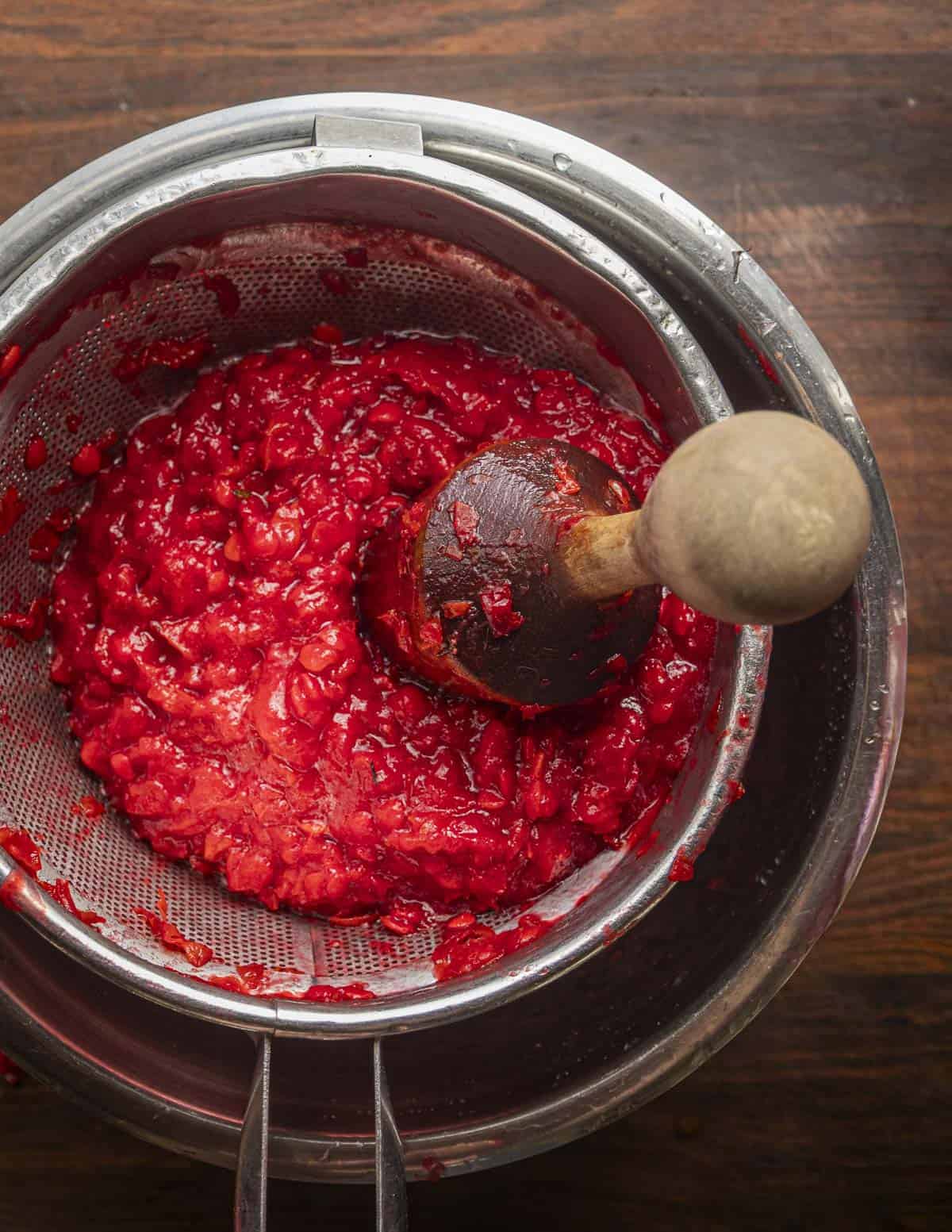 Passing highbush cranberry puree through a strainer. 