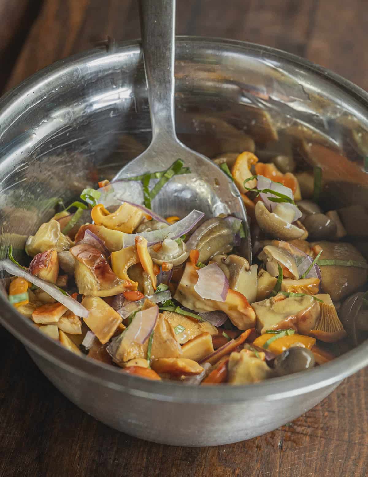 A spoon in a bowl of mushroom ceviche stirring and incorporating ingredients. 