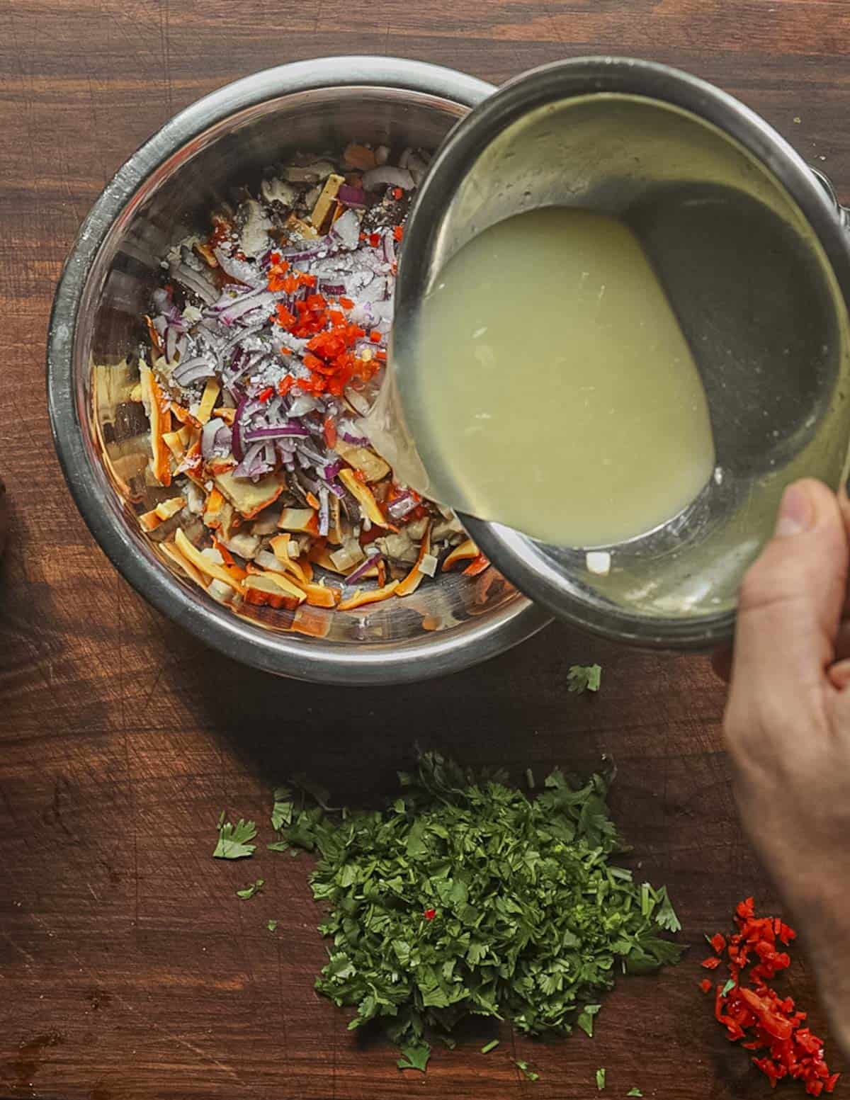 Pouring lime juice into a bowl of mushroom ceviche. 