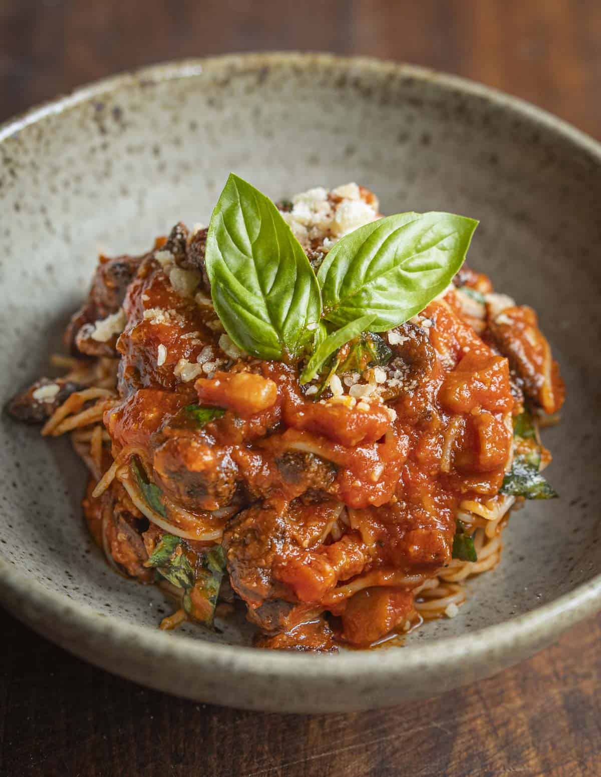 Capellini pasta with fresh tomato sauce and puffball mushrooms garnished with parmesan cheese and fresh basil leaves. 