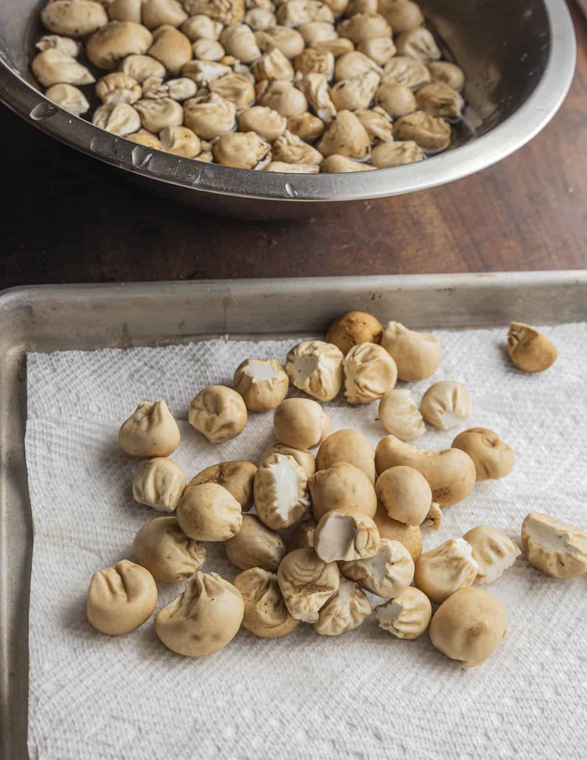 Cleaning puffball mushrooms with water in a bowl and laying them out on a baking sheet lined with paper towels to dry. 