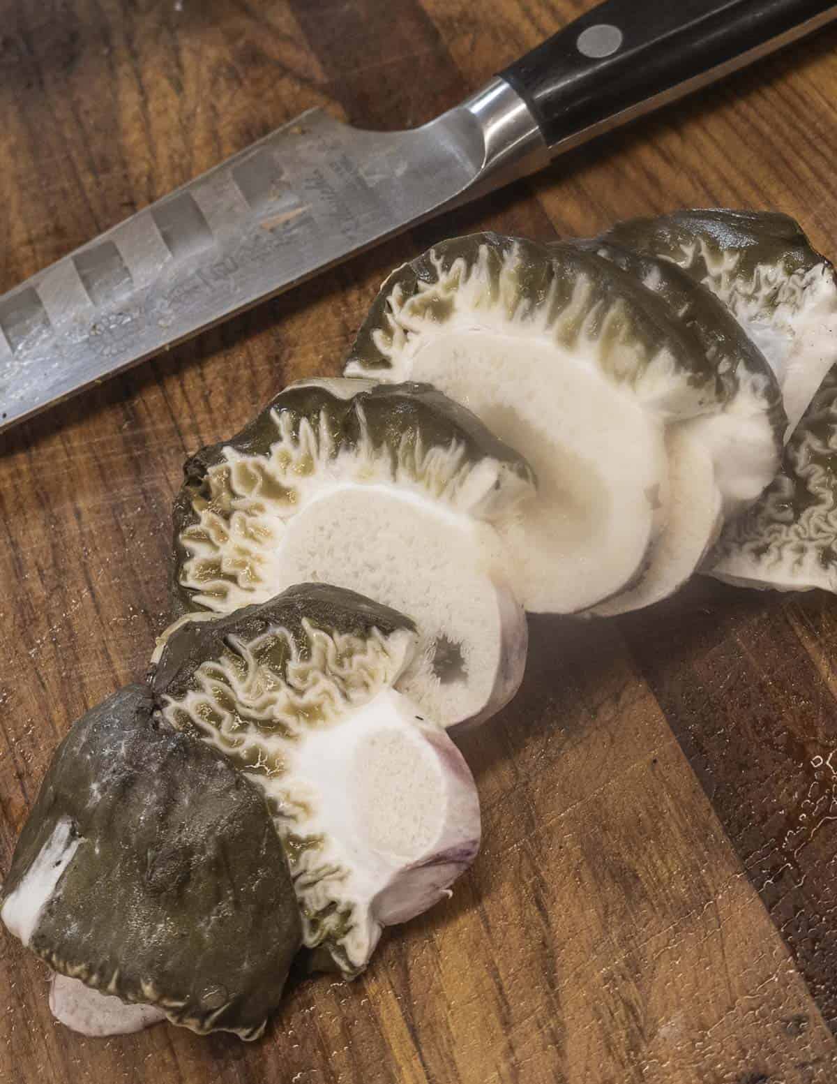 A sliced stinkhorn egg showing green spore material next to a paring knife. 