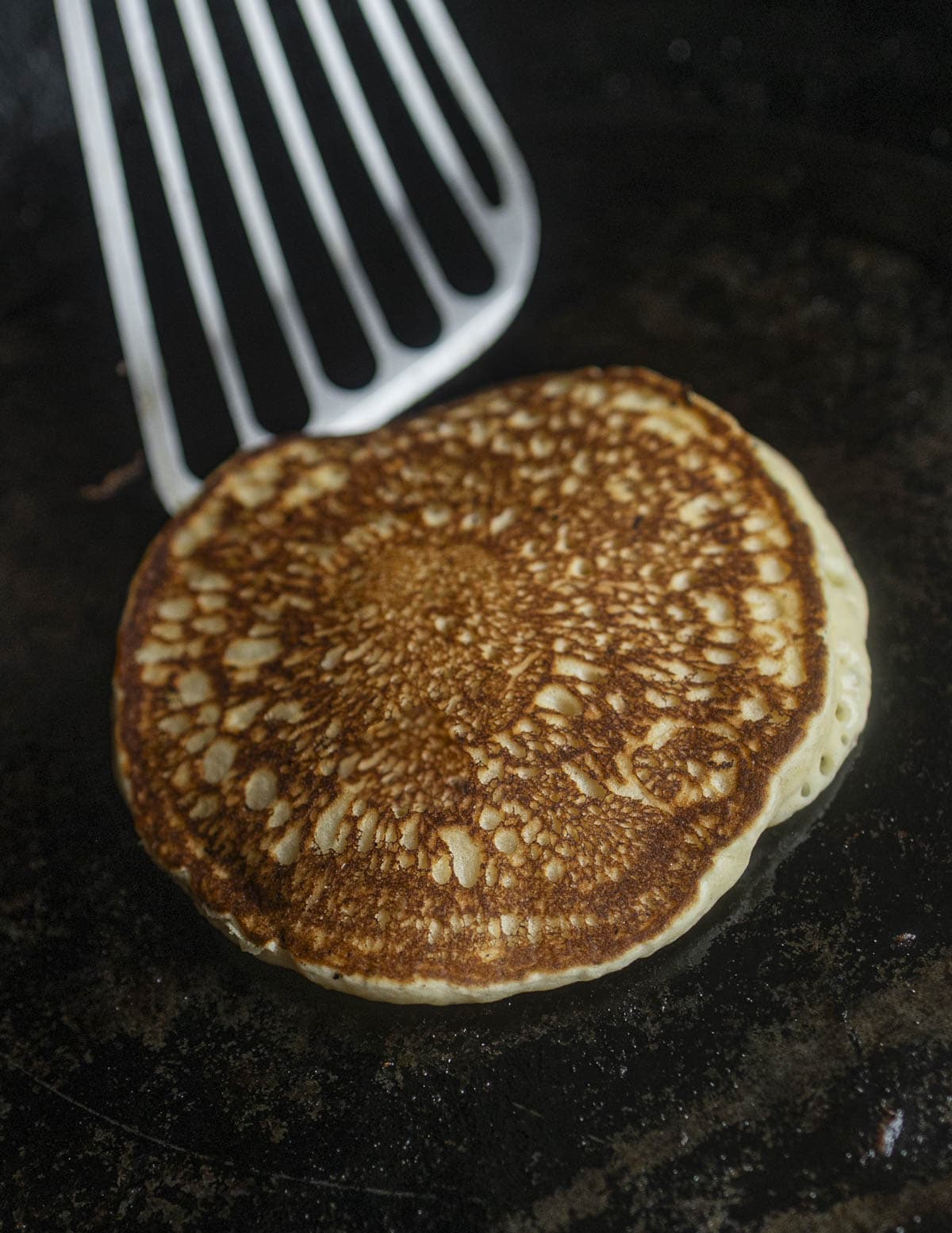 Flipping a golden brown pancake with a spatula. 