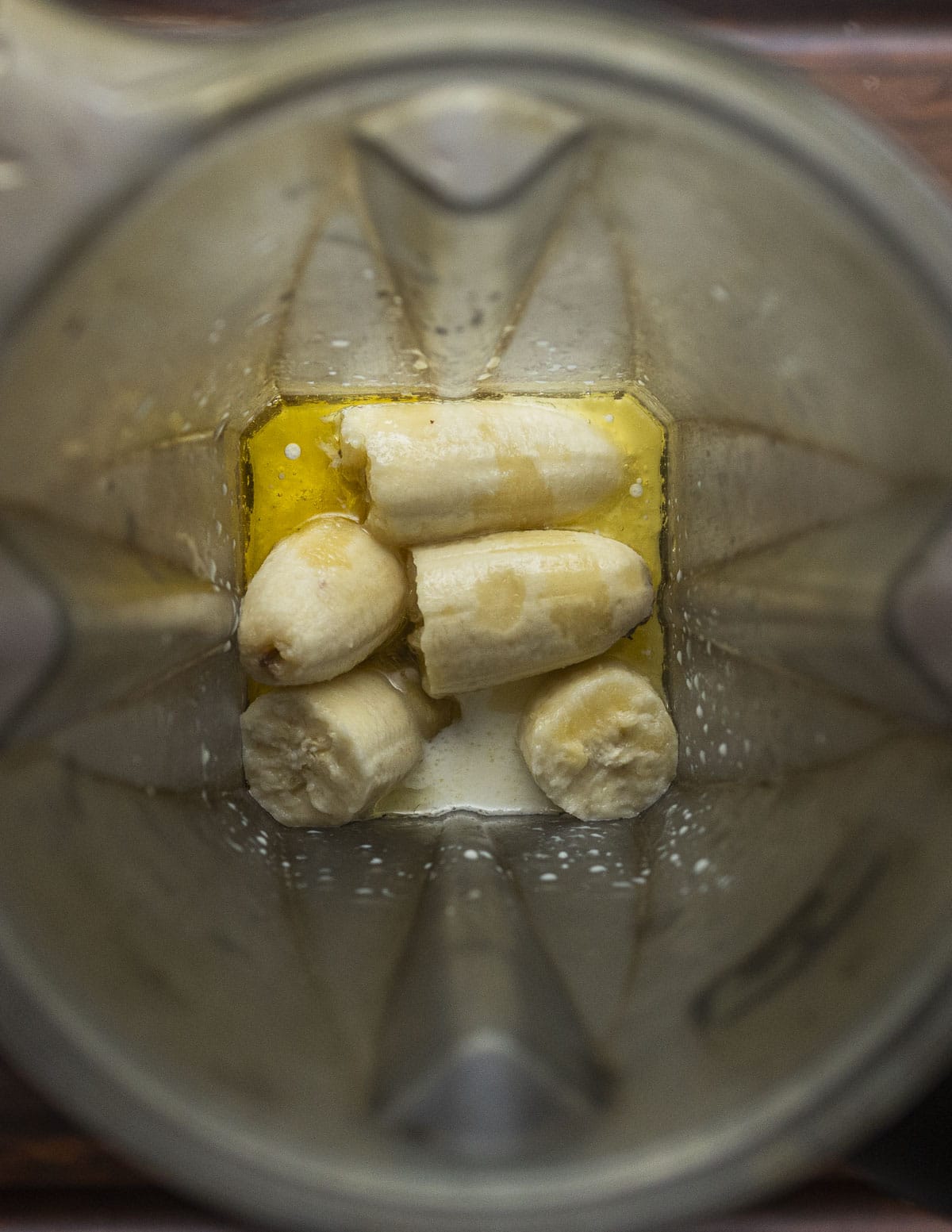 A blender filled with bananas, maple syrup, milk and vanilla. 