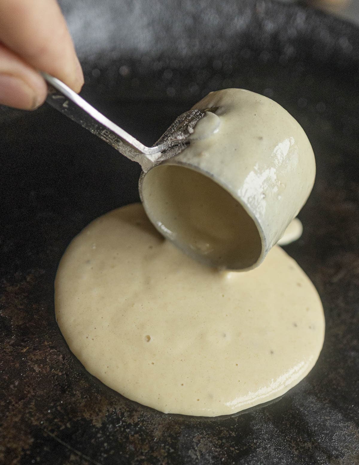 Pouring pancake batter into a pan. 