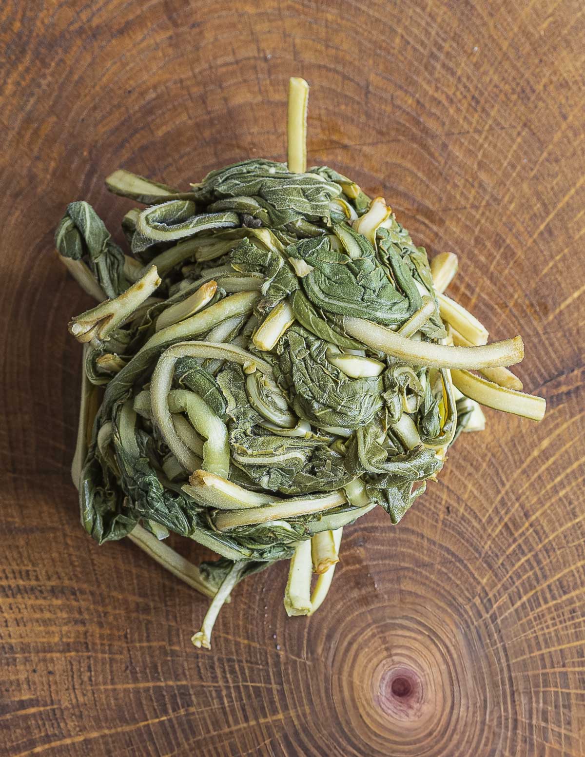 Balled up, cooked evening primrose leaves on a wood background. 