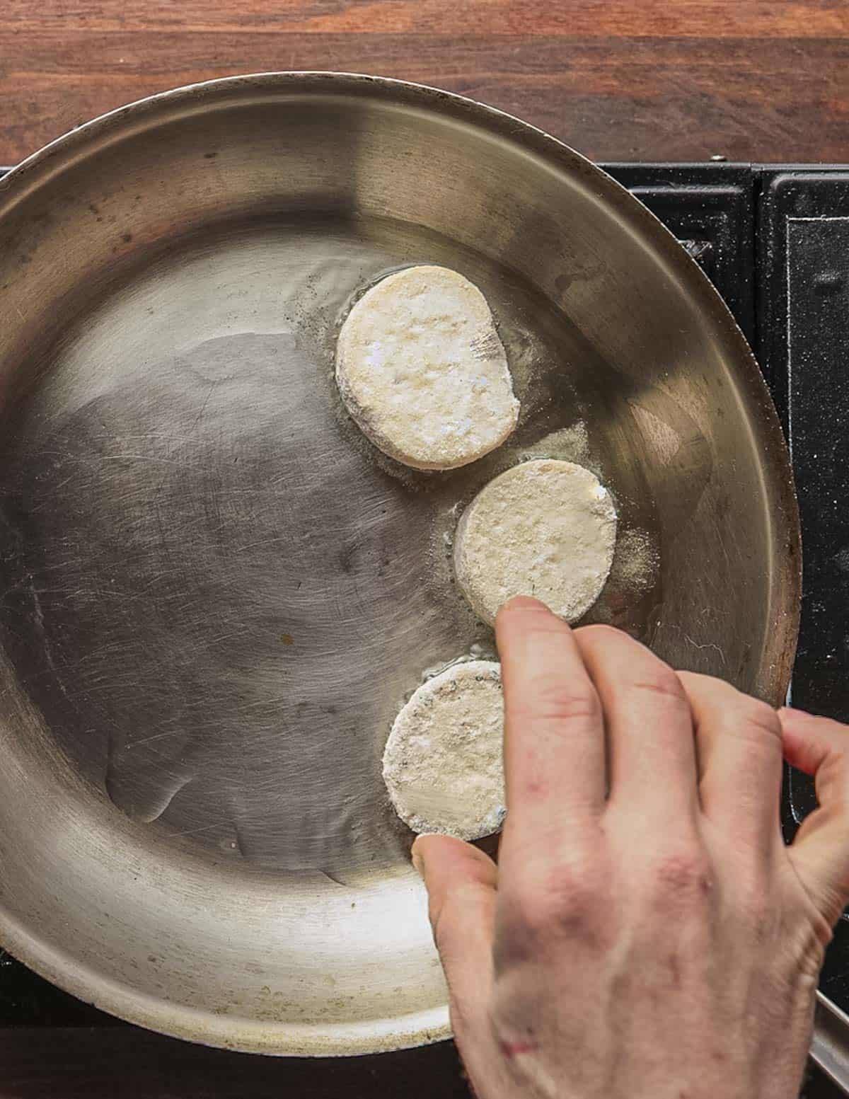 Adding floured, thick slices of King oyster mushroom to hot oil in a sauté pan.