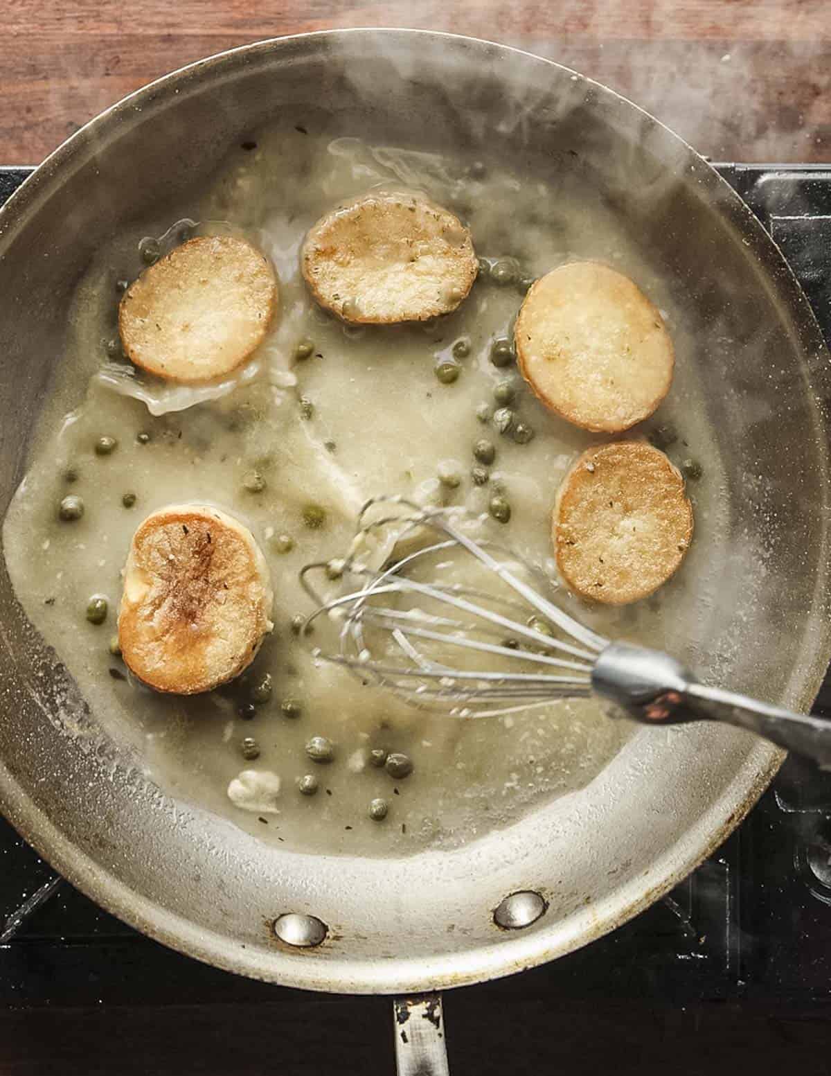 An instructional image showing whisking a lemon caper sauce for a mushroom scallop recipe.