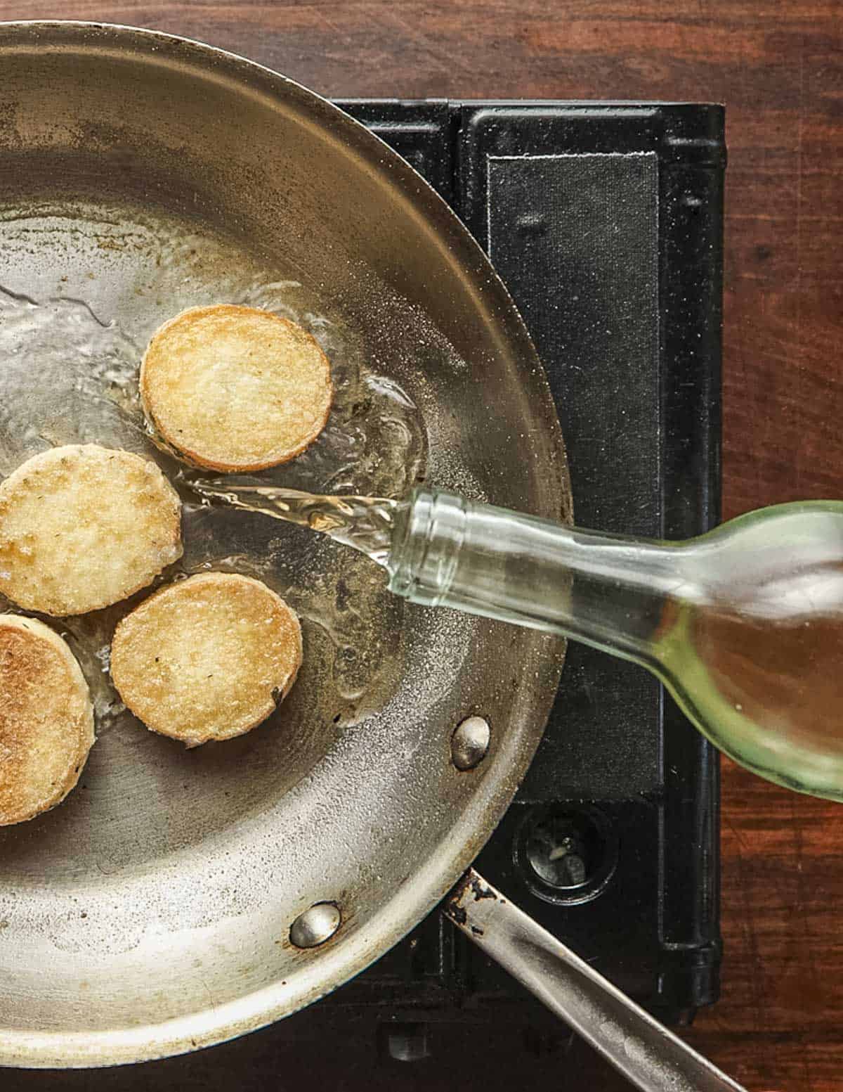 Deglazing a pan of mushroom scallops with dry white wine.
