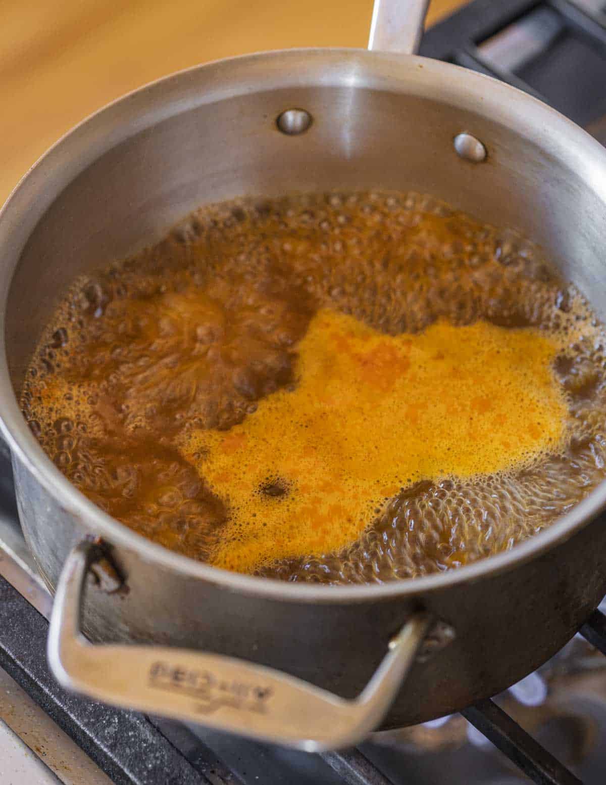 Boiling lobster stock in a pot to reduce it down to a concentrate.