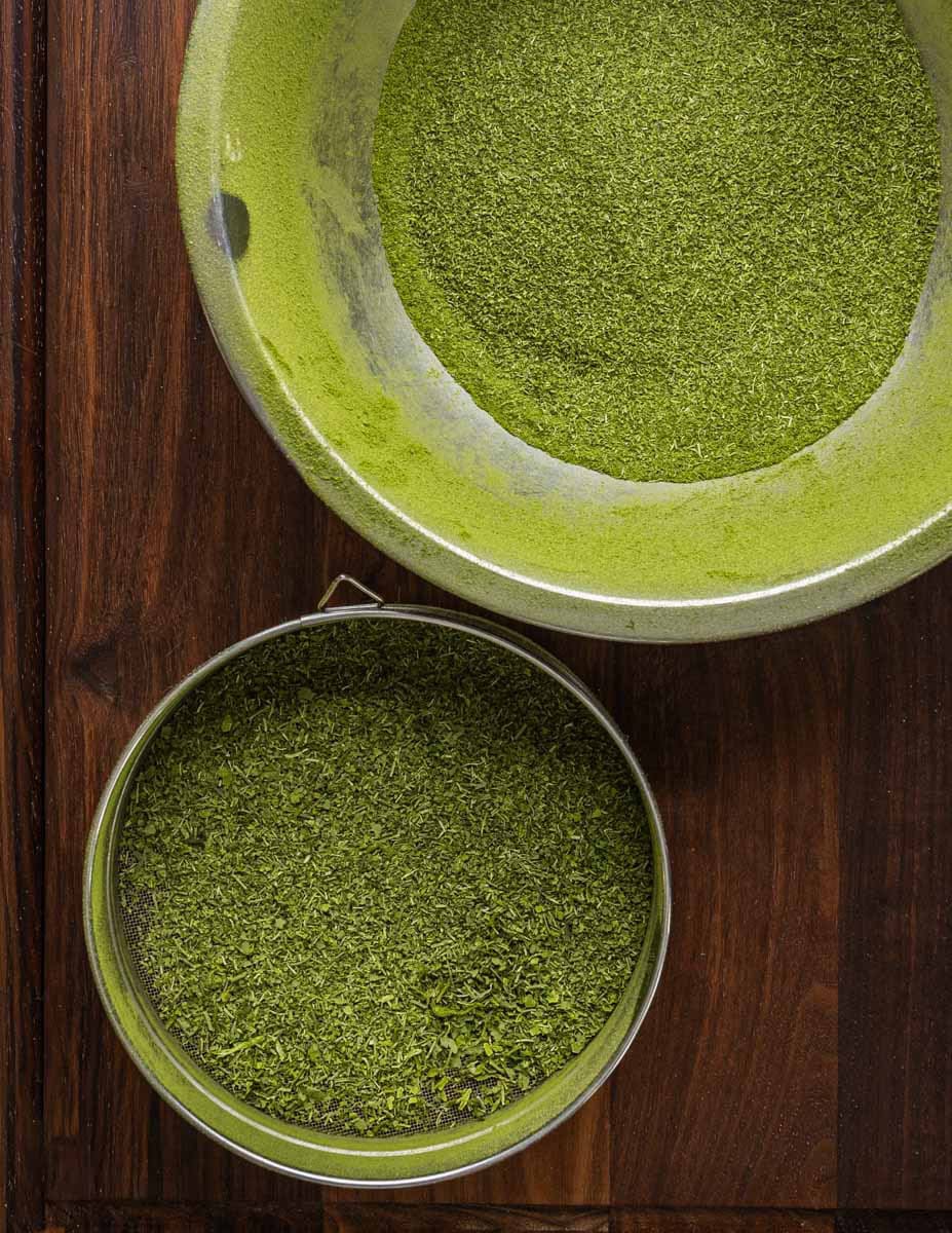 Sifting dehydrated mallow greens into a bowl.