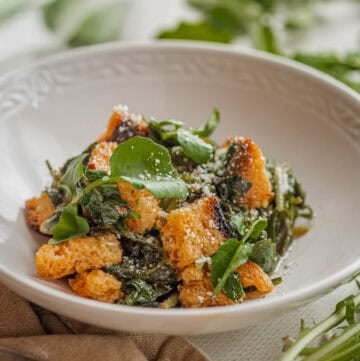 A bowl of pane cotto with wild greens, olive oil and parmesan cheese.