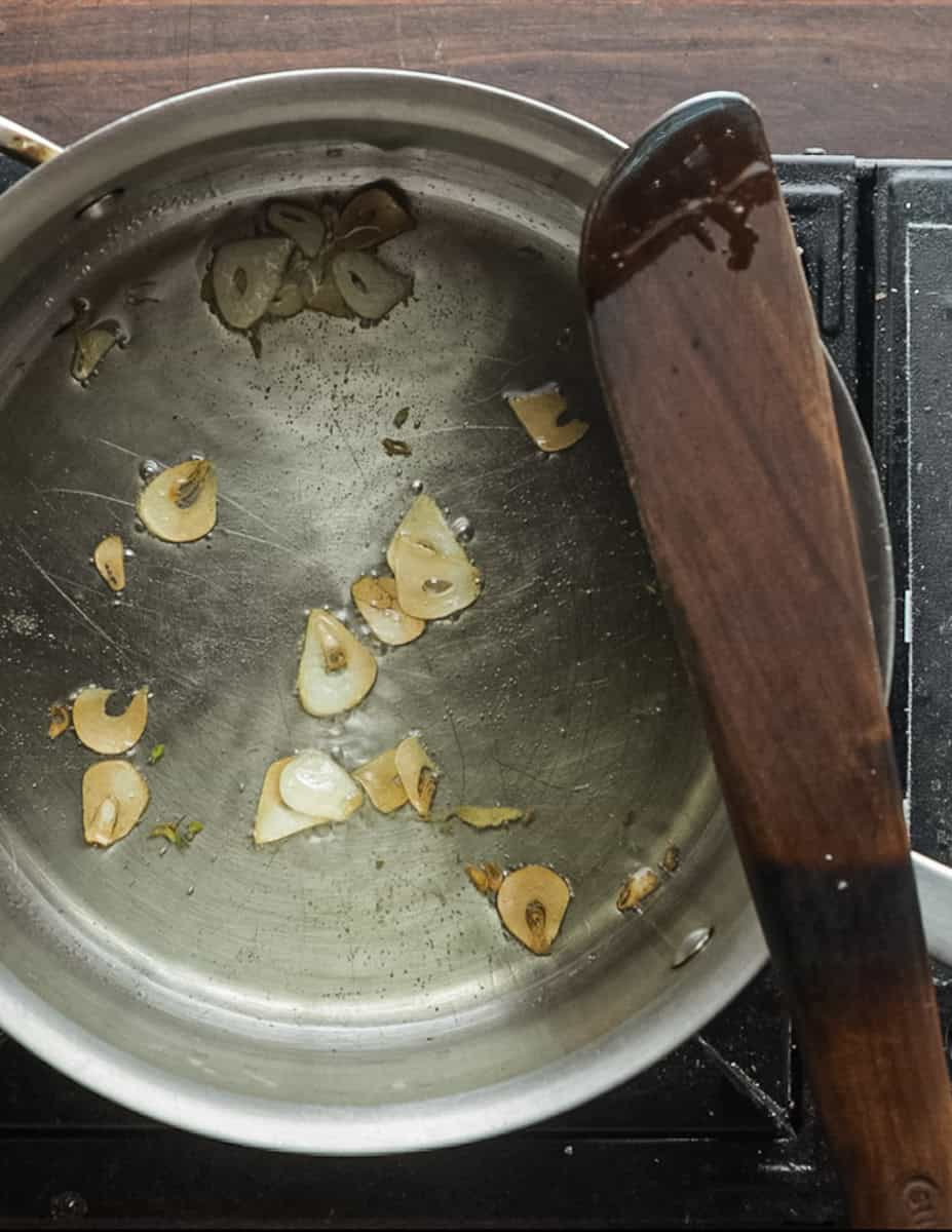 Cooking sliced garlic in a pan until it turns golden brown.