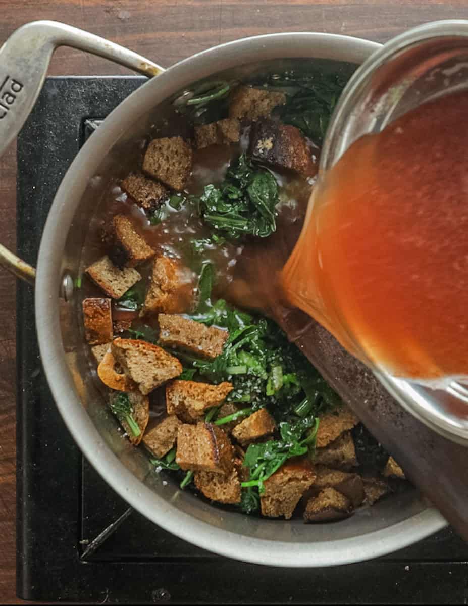 Adding tomato and stock to a pan of pane cotto.