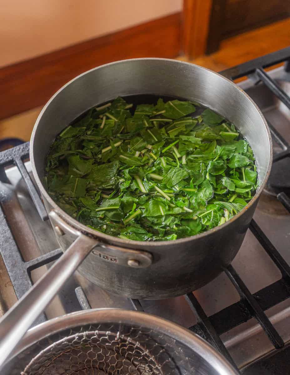 Blanching wild greens in salted water for pane cotto.